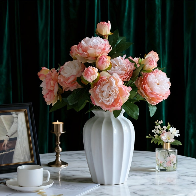 Artificial blush pink peony bouquet in white ribbed vase on marble table with brass candle for elegant french home decor