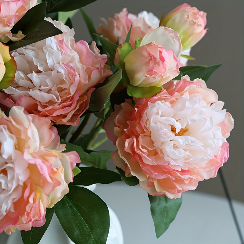 Closeup detail of artificial blush pink peony flower showing pink white gradient petals with light yellow center and bud with green leaves for product detail