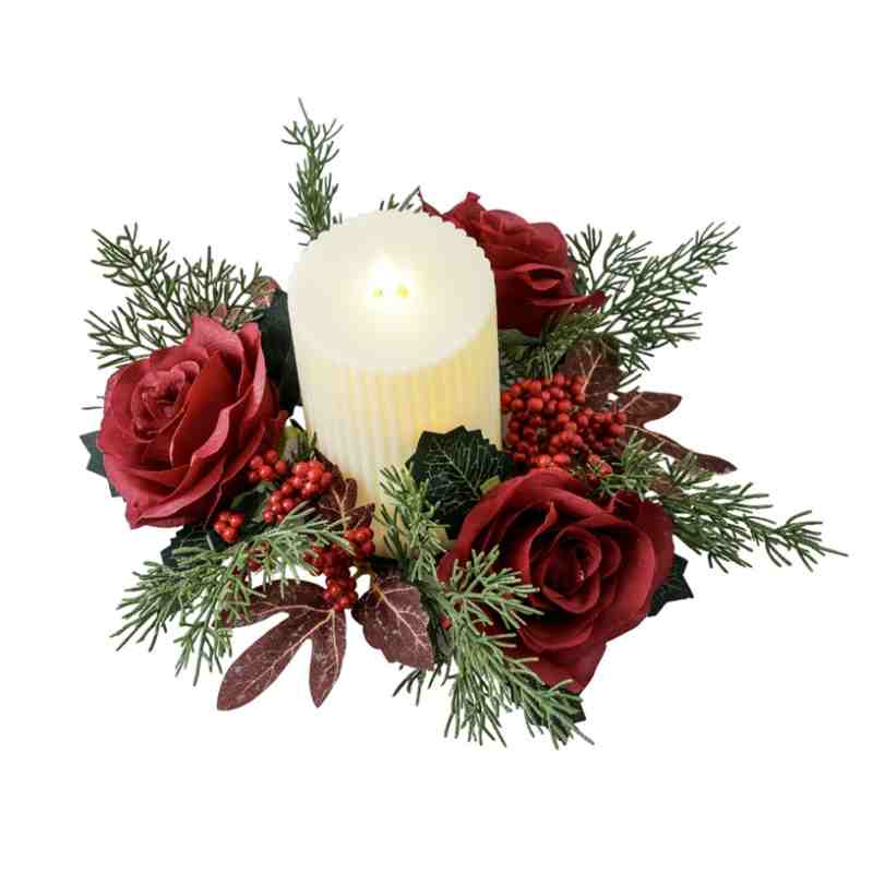 Christmas candle ring with burgundy roses, red berries and green cypress surrounding ribbed white pillar candle on isolated white background