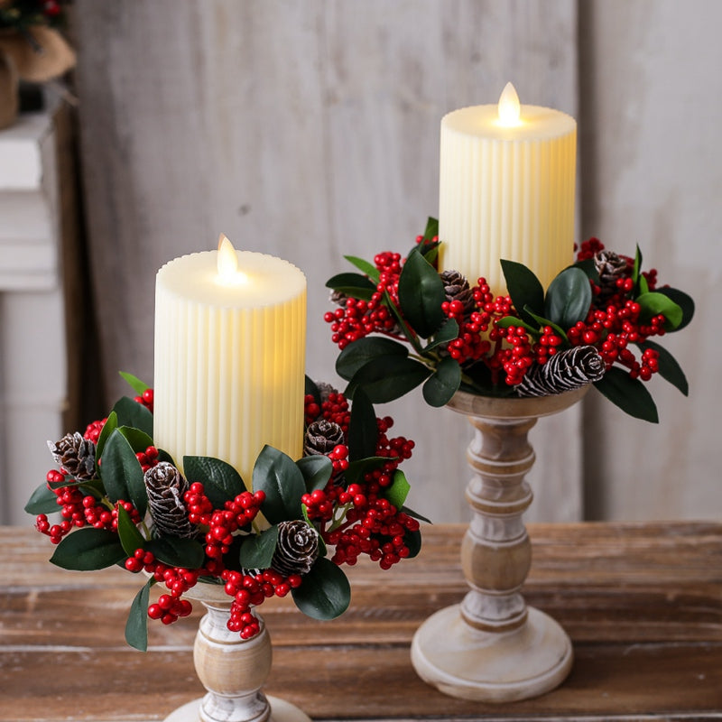 Artificial christmas candle ring wreath with red berries and pine cones placed around led pillar candle on candlestick