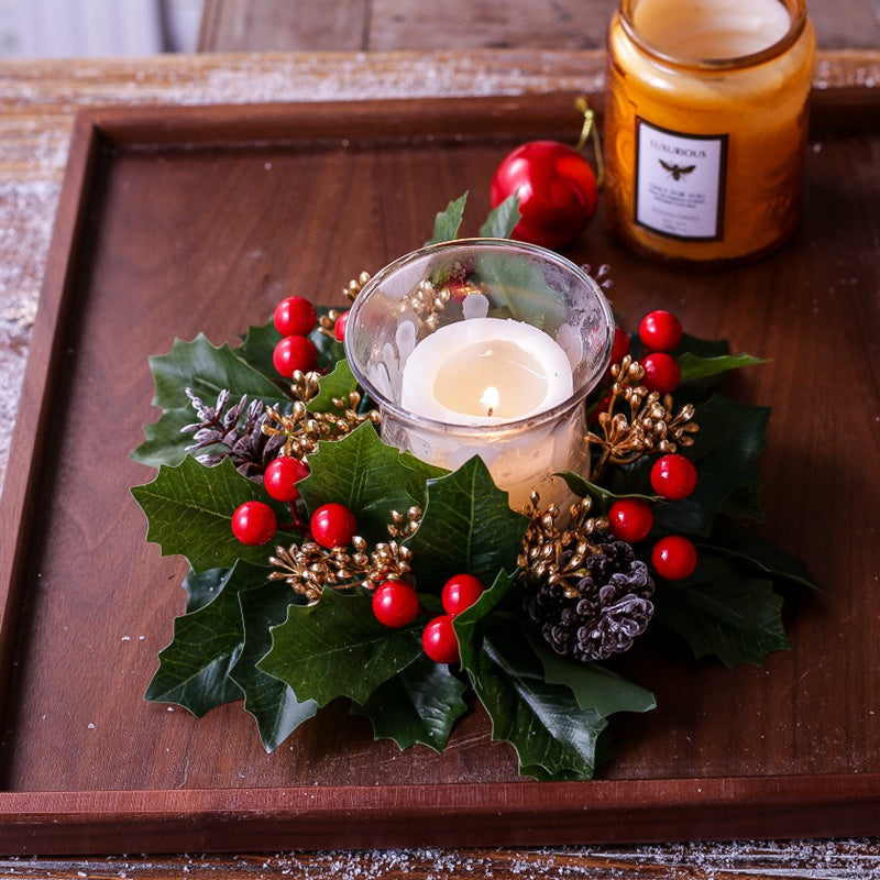 Christmas holly candle ring decor on wooden tray with candle, red berries and frosted pinecones for winter home styling