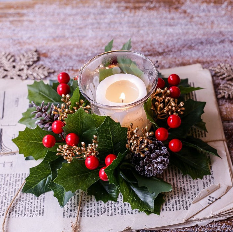 Artificial holly candle ring styled on vintage paper, red berries and pinecones for elegant Christmas table centerpiece