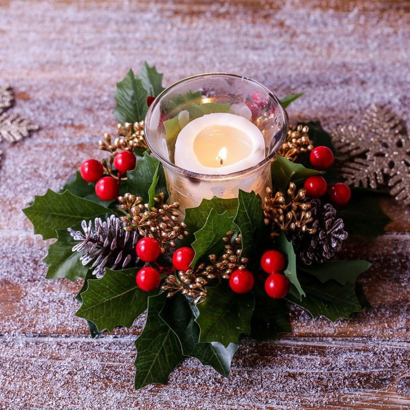 Close-up view of Christmas holly candle ring, red berries, frosted pinecone and green holly leaves around candle holder