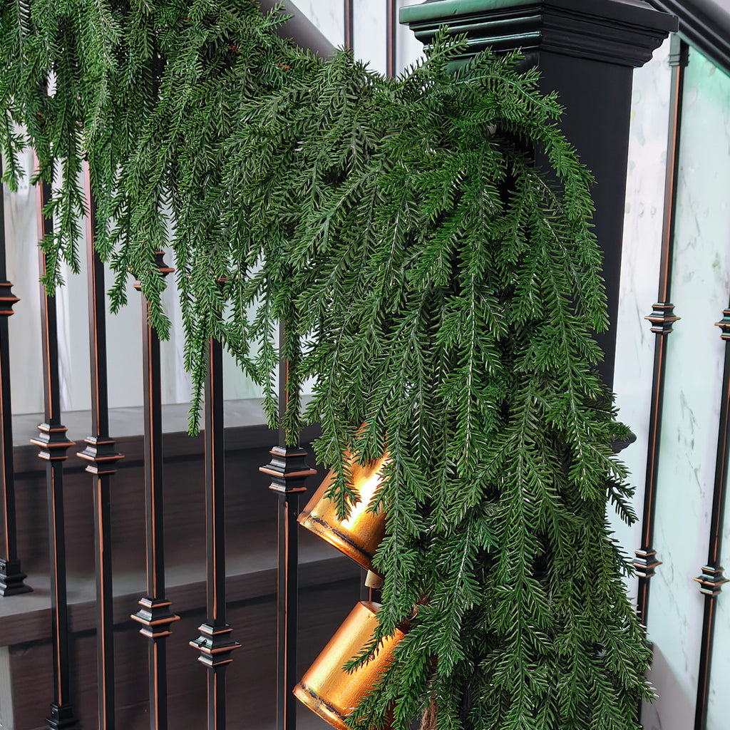 Full length realistic norfolk pine christmas garlands draped over modern black metal stair balusters