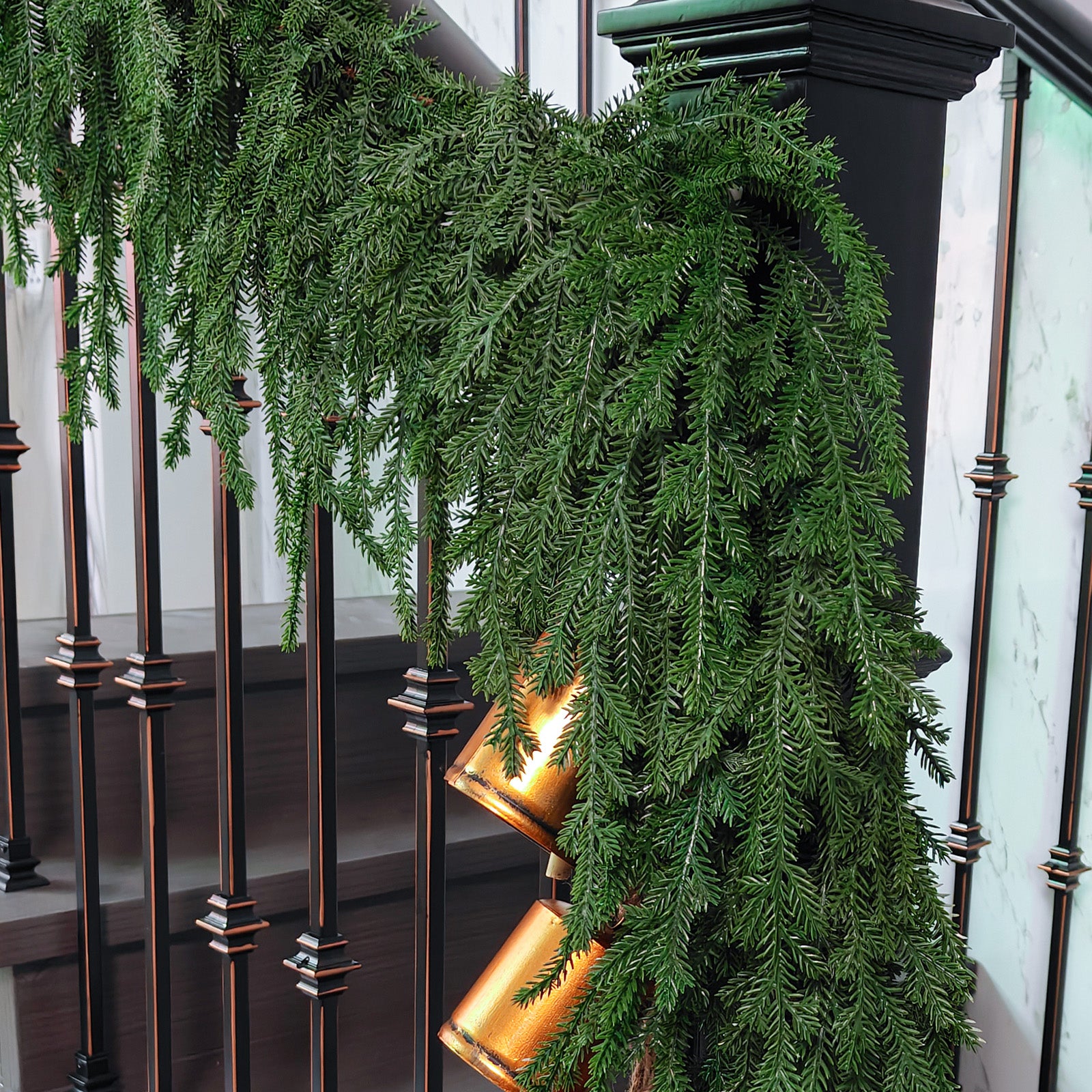 Full length realistic norfolk pine christmas garlands draped over modern black metal stair balusters