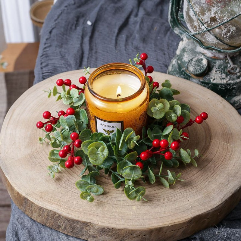 Top view eucalyptus red berry candle ring with amber candle on natural wood slice, Christmas table centerpiece