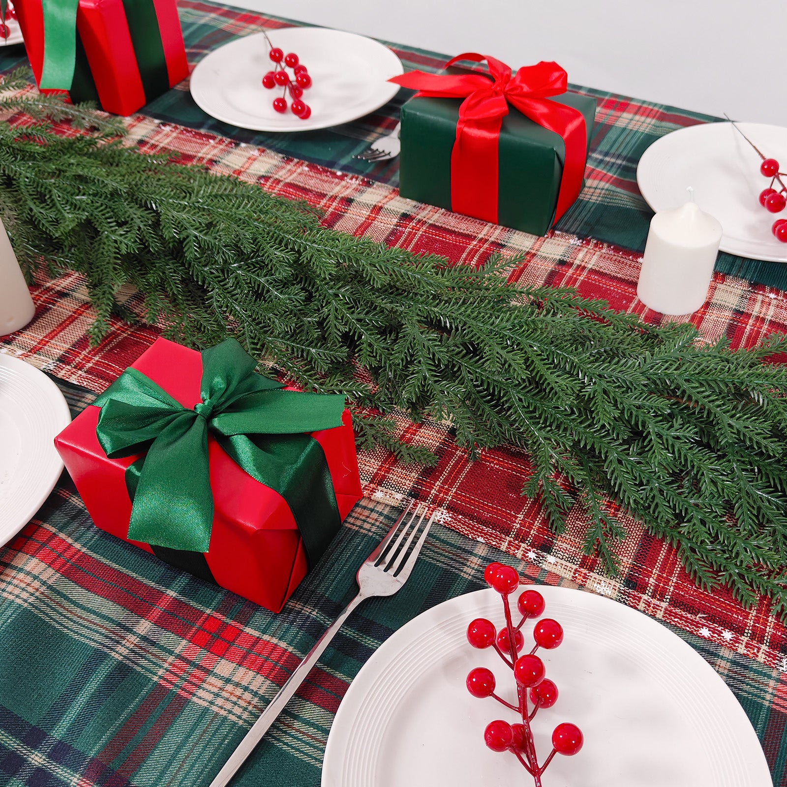 Drooping lush norfolk pine christmas garlands used as table runner on red green plaid holiday dining table