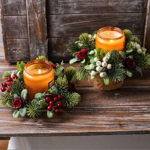 Two styles of christmas candle rings, red berry rose and white berry decor, paired with amber jar candles on weathered wooden table