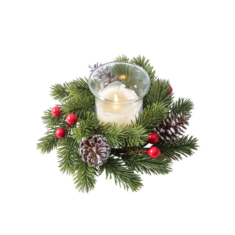 Artificial pine Christmas candle ring with red berries and frosted pinecones around clear glass candle, isolated on white background