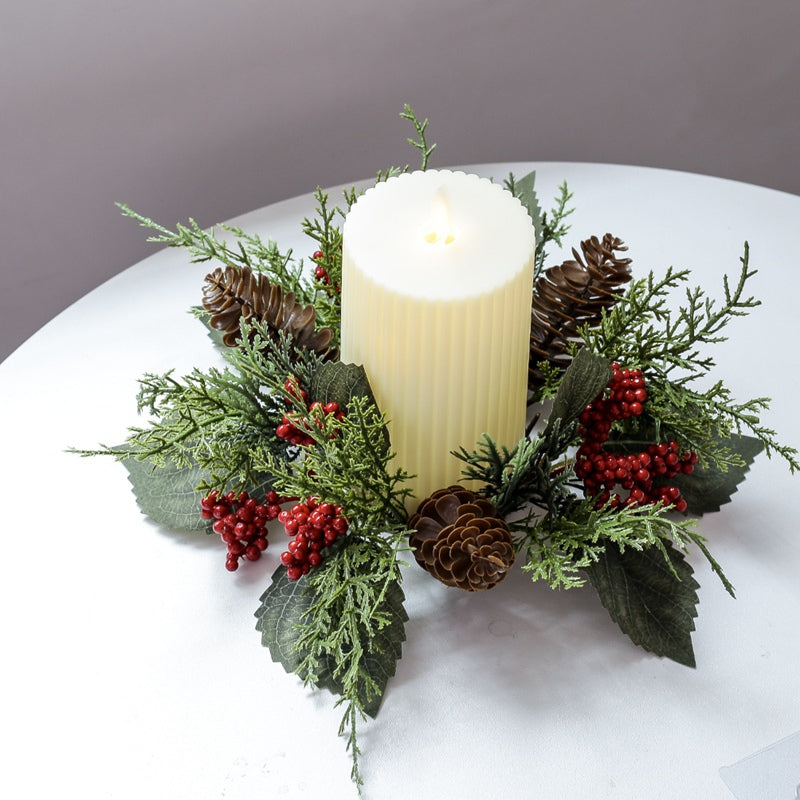 Artificial Christmas candle wreath ring with pinecones, red berries and green foliage surrounding pillar candle on clean white round table
