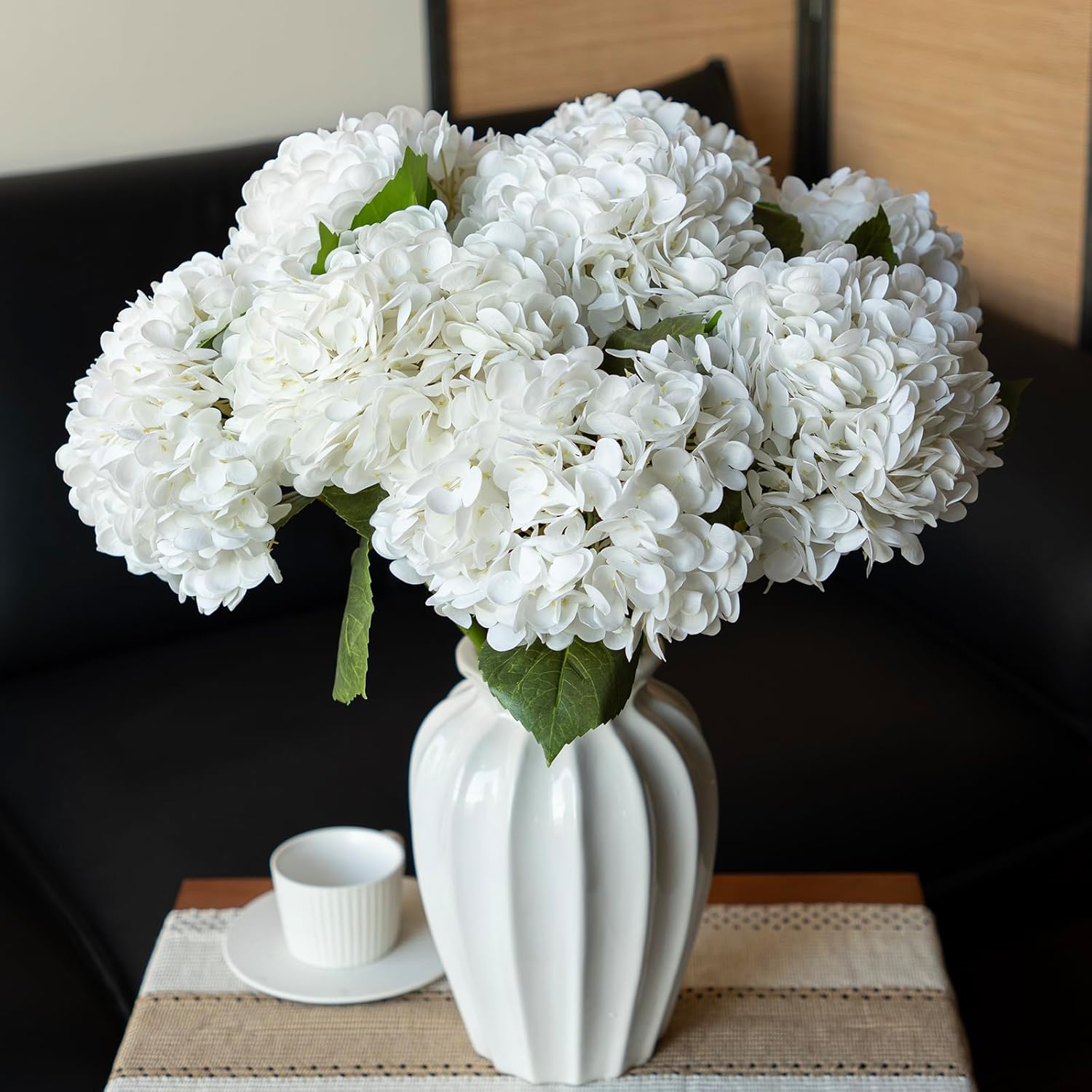Voluminous fluffy white hydrangea faux flowers complete arrangement in ribbed ceramic vase for living room table decor