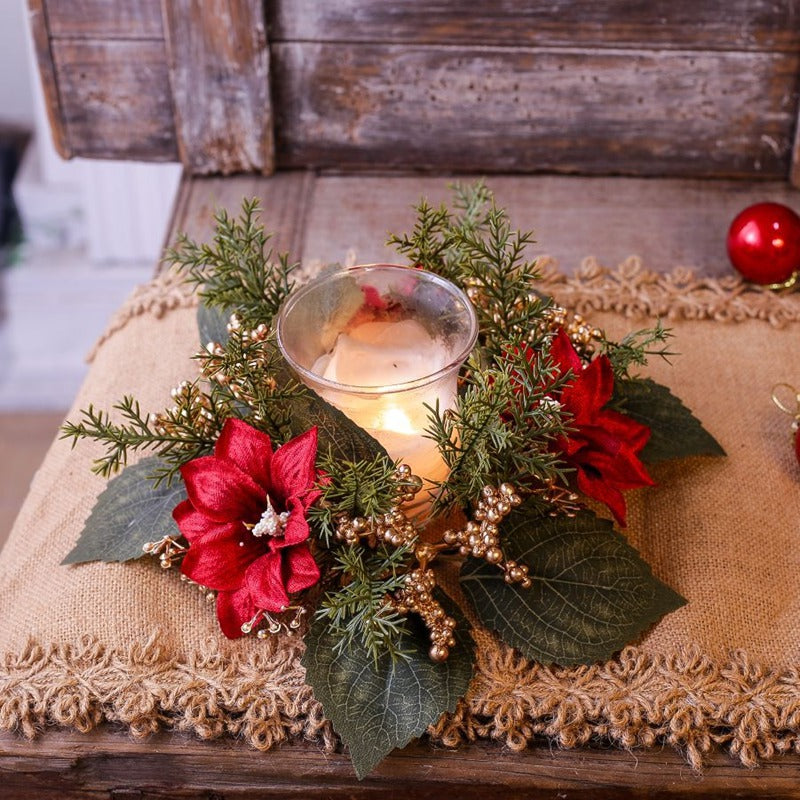 Artificial poinsettia candle ring with gold berries and green cedar surrounding glass candle on burlap runner rustic Christmas decor
