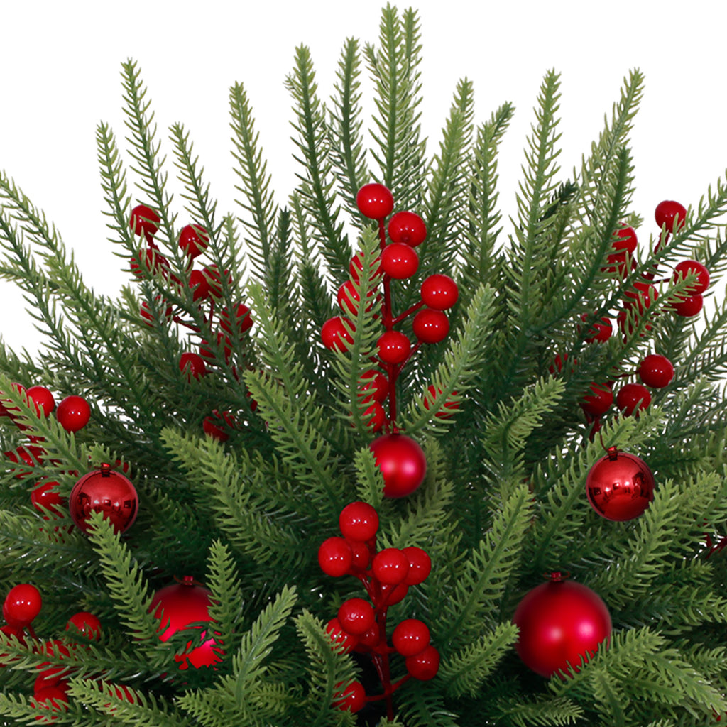 Close up mini christmas tree dense green pine sprigs accented with glossy red balls and bright red berries