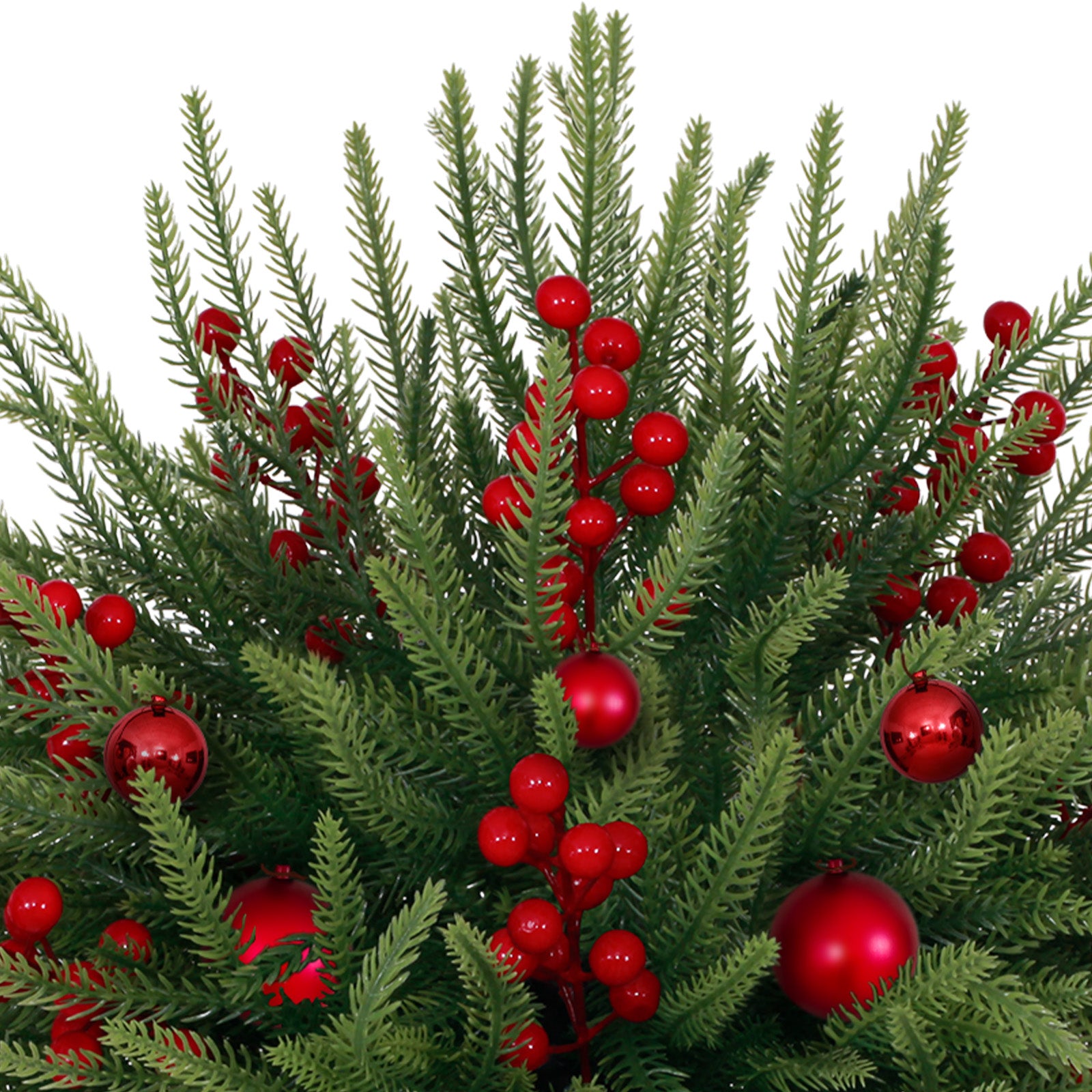 Close up mini christmas tree dense green pine sprigs accented with glossy red balls and bright red berries