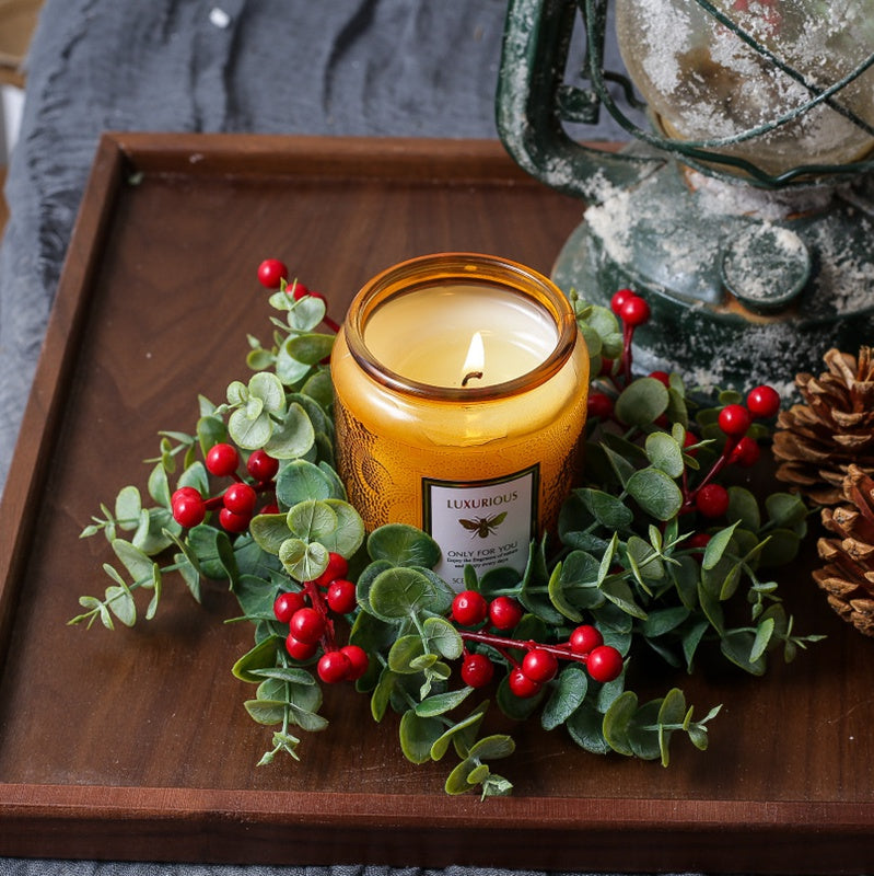 Top view eucalyptus red berry candle ring with amber candle on natural wood slice, Christmas table centerpiece