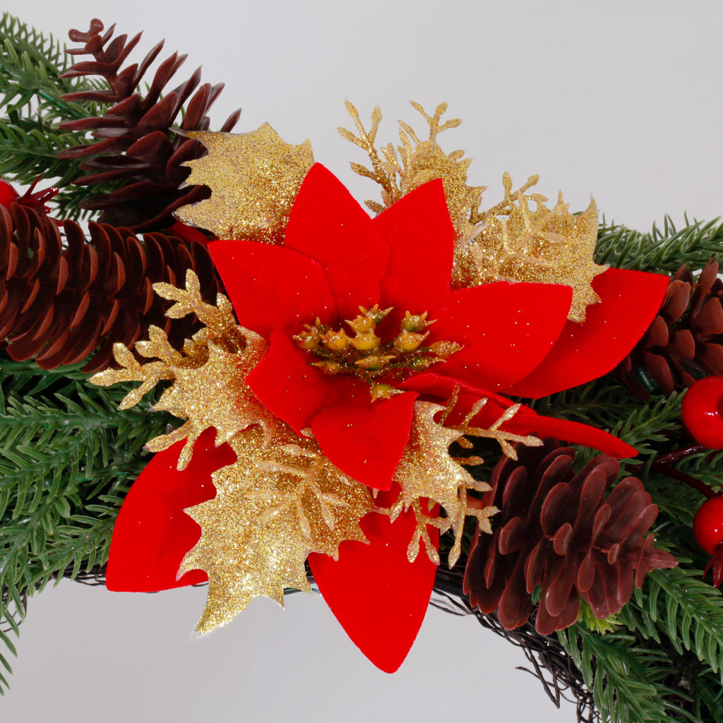 Closeup festive flower wreath with red poinsettia, gold glitter leaves, pinecones and bright red berry sprigs