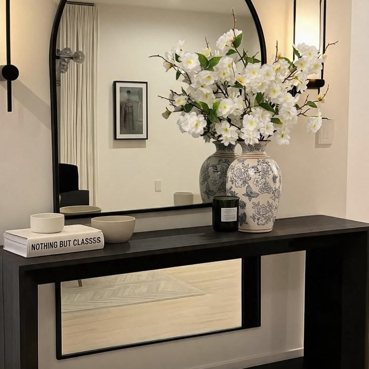 Tall branching white blossom silk flowers arranged in ceramic vase for modern entryway console table decor