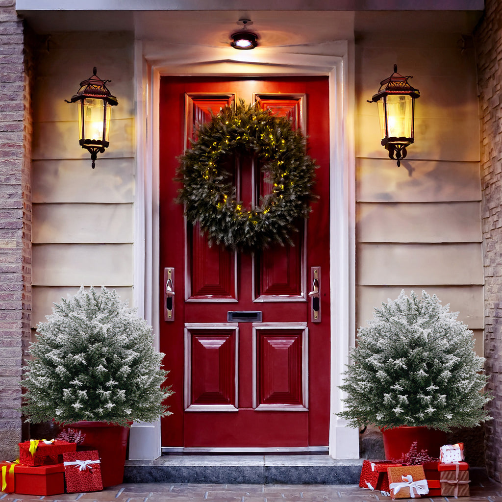 Matching mini snow covered christmas trees placed on both sides of farmhouse front entry door