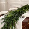 Unadorned realistic cedar artificial christmas garland used as dining table runner for neutral festive table centerpiece