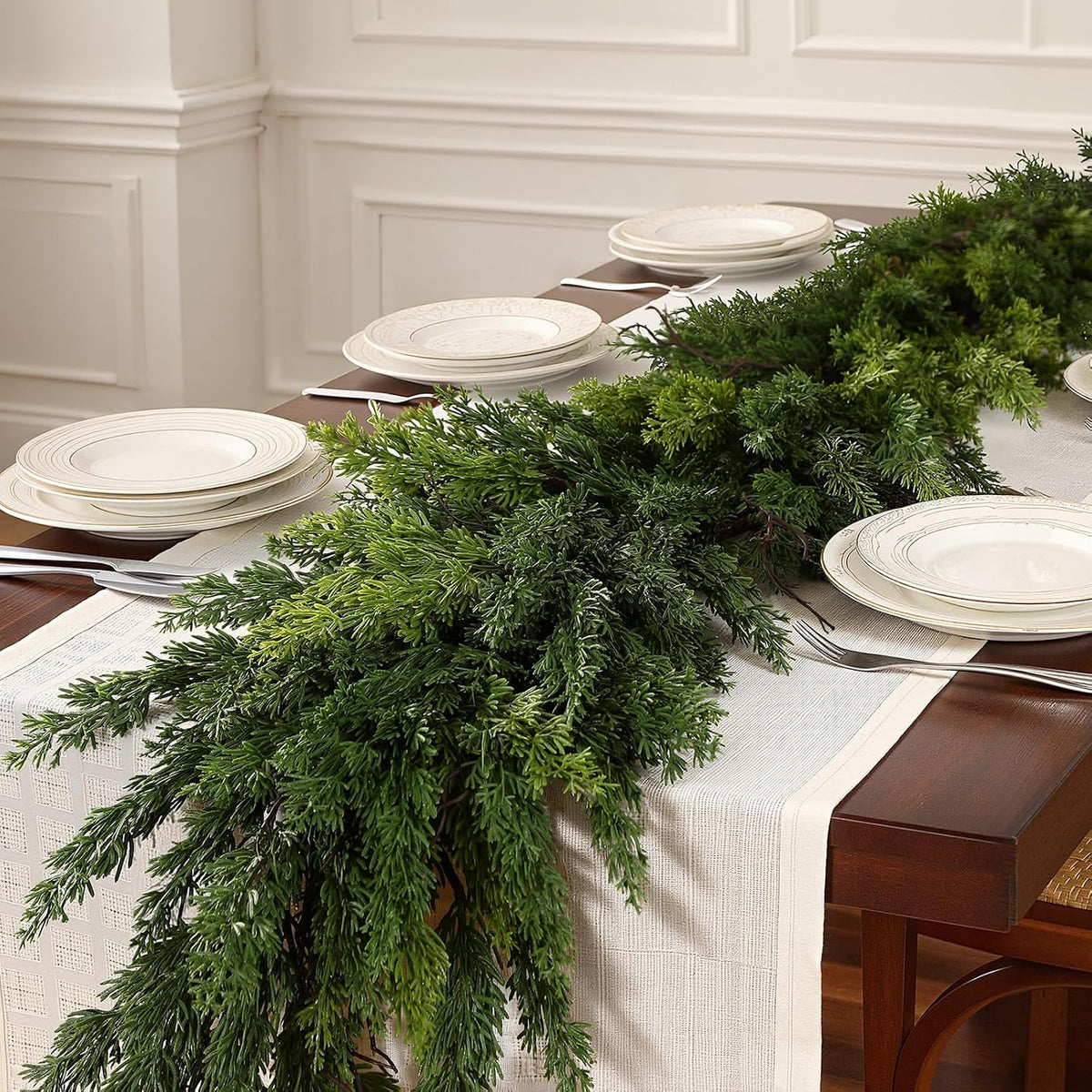 Unadorned realistic cedar artificial christmas garland used as dining table runner for neutral festive table centerpiece
